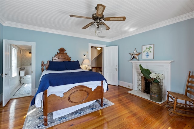 bedroom featuring crown molding, a fireplace with flush hearth, a ceiling fan, wood finished floors, and baseboards