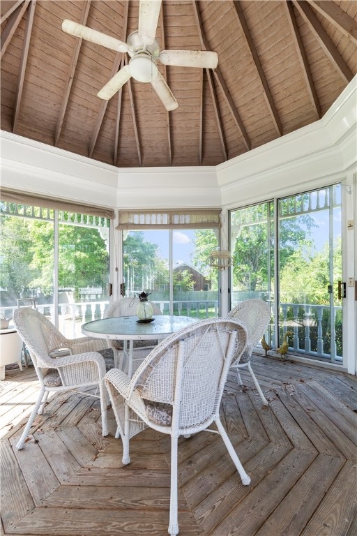 unfurnished sunroom featuring a ceiling fan, wooden ceiling, and lofted ceiling with beams