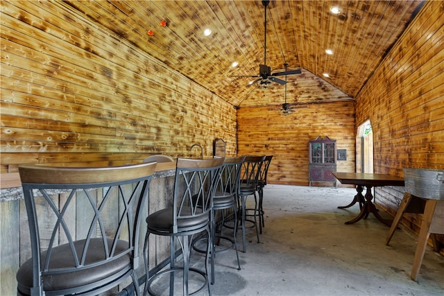 bar with wood ceiling, vaulted ceiling, wood walls, bar, and concrete floors