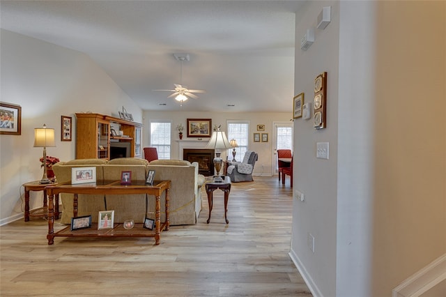 living room with light wood-type flooring, ceiling fan, and lofted ceiling