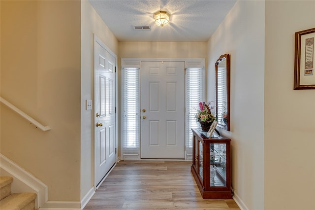 foyer with light wood-type flooring and a textured ceiling