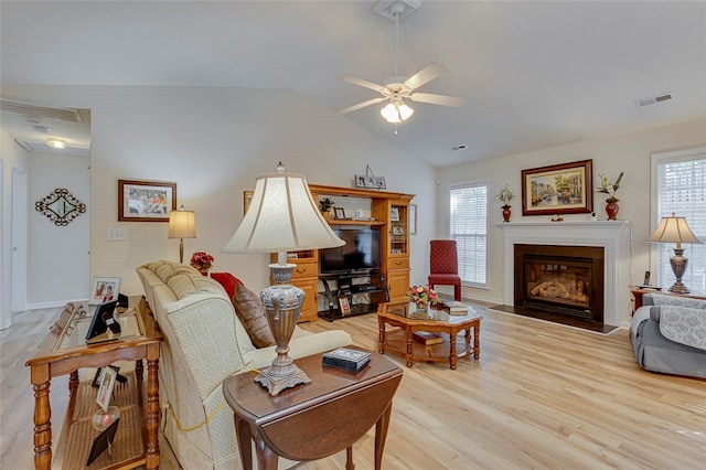 living room with ceiling fan, lofted ceiling, a wealth of natural light, and light hardwood / wood-style floors