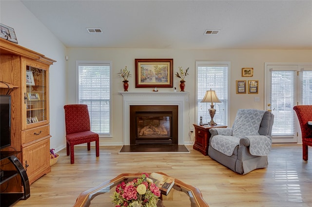 living area with lofted ceiling, plenty of natural light, and light wood-type flooring