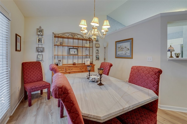 dining area with an inviting chandelier, lofted ceiling, and light hardwood / wood-style floors