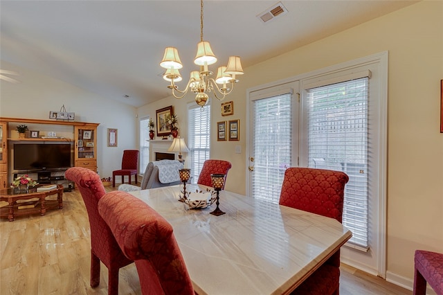 dining space featuring a notable chandelier, lofted ceiling, and light hardwood / wood-style flooring