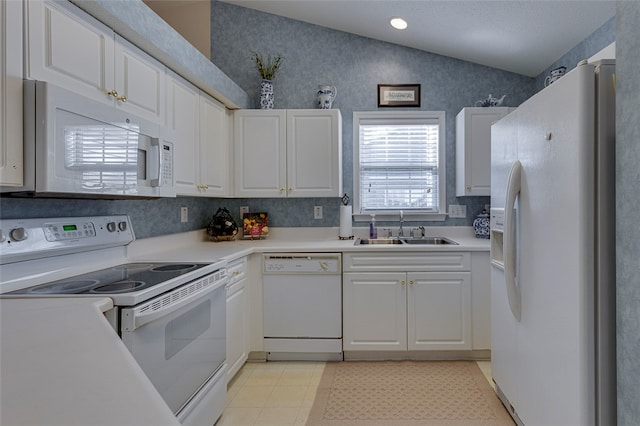 kitchen with lofted ceiling, white appliances, sink, and white cabinetry