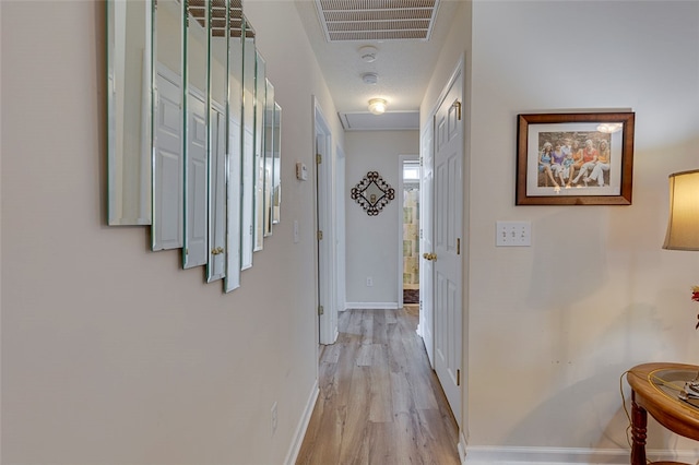 hallway with light wood-type flooring and a textured ceiling