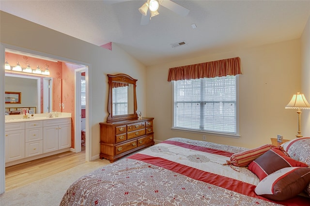 bedroom with ceiling fan, sink, light hardwood / wood-style flooring, ensuite bathroom, and vaulted ceiling