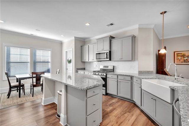 kitchen with light wood-type flooring, gray cabinets, pendant lighting, and stainless steel appliances