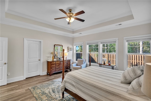 bedroom with ceiling fan, wood-type flooring, crown molding, access to exterior, and a raised ceiling