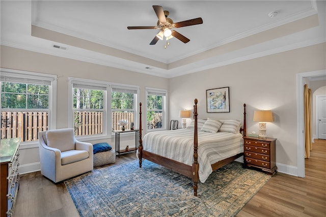 bedroom featuring ceiling fan, light hardwood / wood-style flooring, a raised ceiling, and ornamental molding