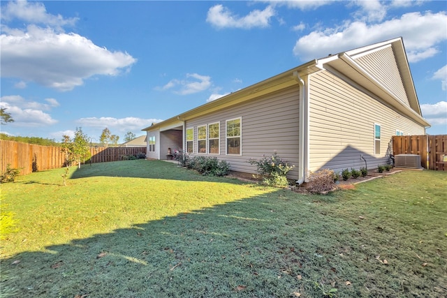 view of side of property with a yard and central AC