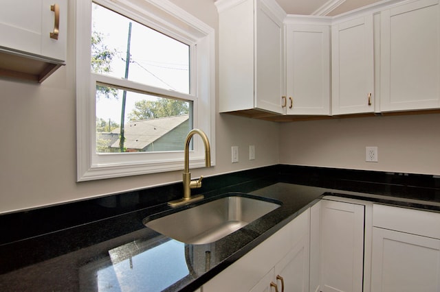 kitchen with ornamental molding, sink, white cabinets, and dark stone countertops