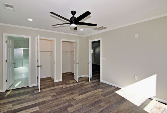 unfurnished bedroom featuring ensuite bathroom, dark hardwood / wood-style flooring, a walk in closet, and ceiling fan