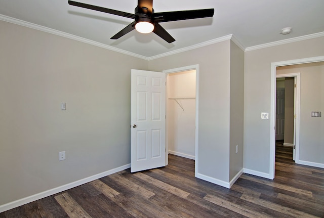 unfurnished bedroom with a walk in closet, a closet, ceiling fan, crown molding, and dark hardwood / wood-style floors