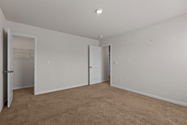 unfurnished bedroom with a closet, carpet floors, and a walk in closet