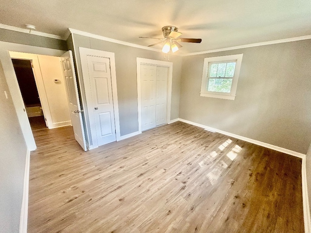 unfurnished bedroom with light hardwood / wood-style floors, ornamental molding, multiple closets, and ceiling fan