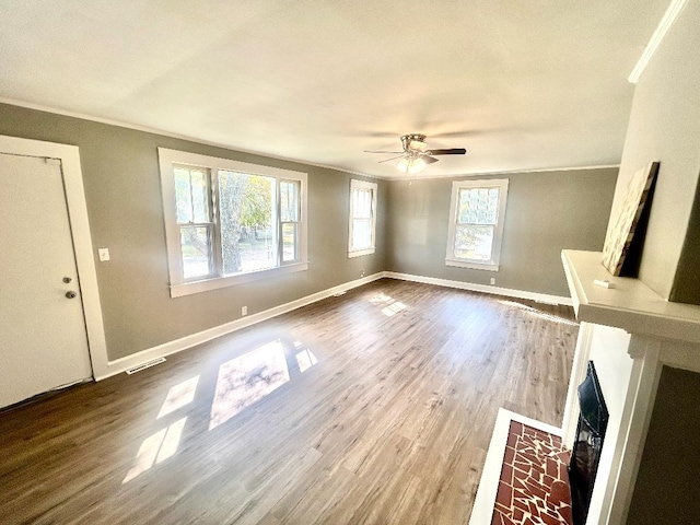 unfurnished living room with ornamental molding, a healthy amount of sunlight, wood-type flooring, and ceiling fan