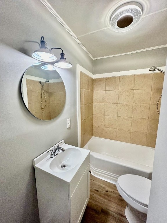 full bathroom featuring hardwood / wood-style floors, toilet, ornamental molding, vanity, and tiled shower / bath combo