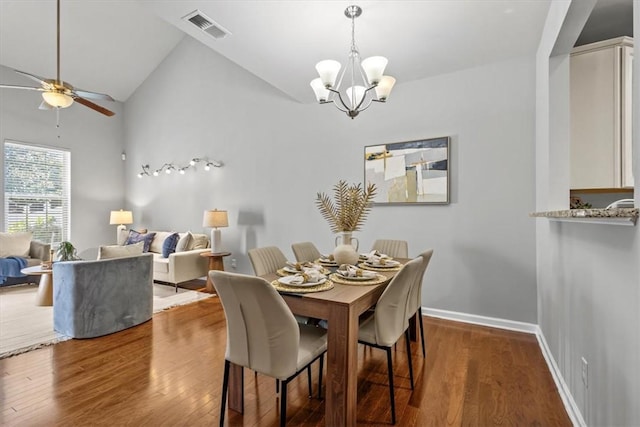 dining room with ceiling fan with notable chandelier, dark hardwood / wood-style floors, and high vaulted ceiling