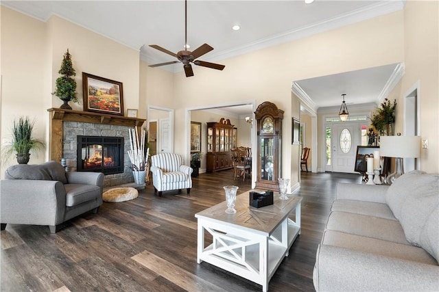 living area featuring recessed lighting, a stone fireplace, dark wood-style flooring, and ornamental molding