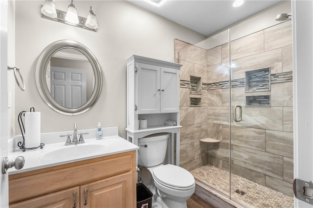 bathroom with a shower stall, toilet, and vanity