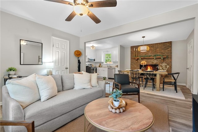 living area featuring light wood-style floors, ceiling fan, and baseboards