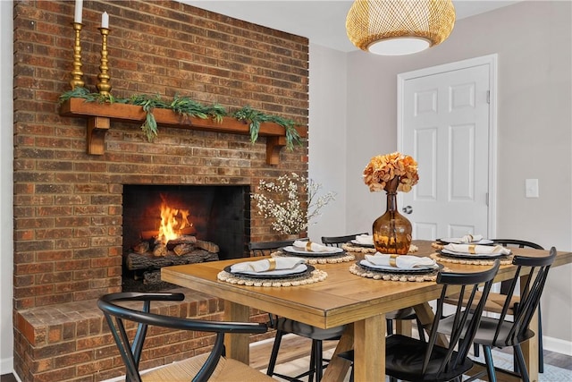 dining space with hardwood / wood-style floors and a brick fireplace