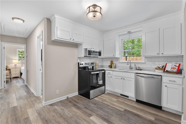 kitchen with sink, light hardwood / wood-style flooring, tasteful backsplash, white cabinetry, and stainless steel appliances