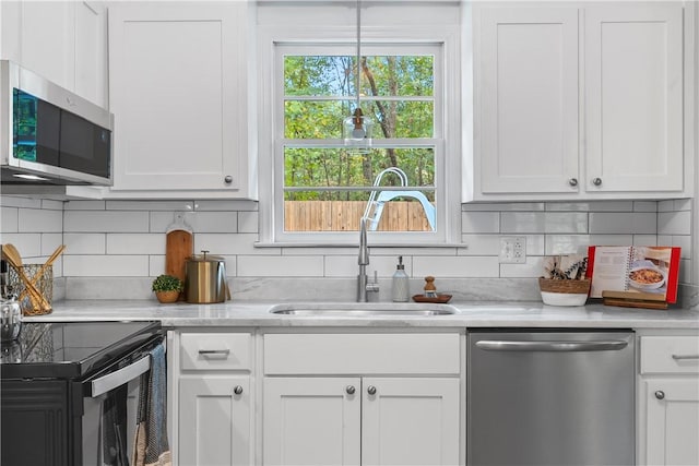 kitchen with backsplash, stainless steel appliances, white cabinetry, and sink