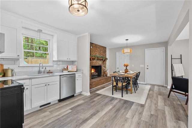 kitchen featuring pendant lighting, white cabinets, sink, stainless steel dishwasher, and decorative backsplash