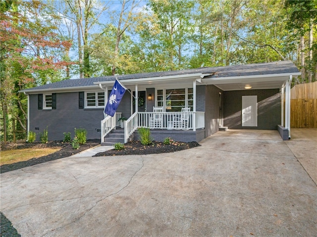 ranch-style home featuring a porch, an attached carport, brick siding, concrete driveway, and crawl space