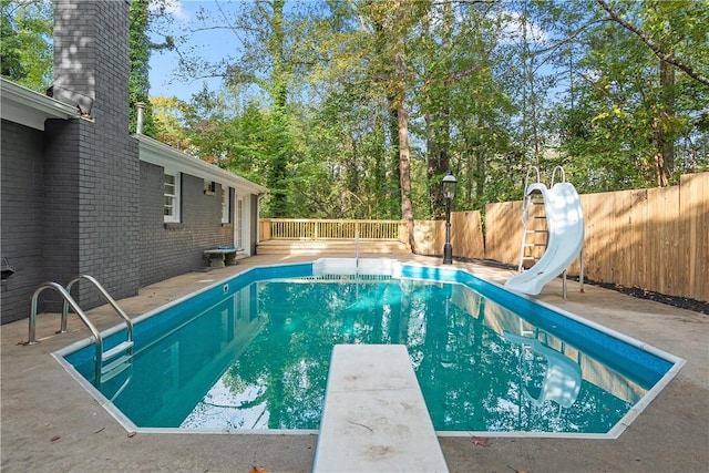 view of swimming pool featuring a deck, a diving board, and a water slide