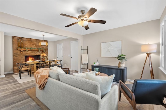 living room with hardwood / wood-style floors, a brick fireplace, and ceiling fan