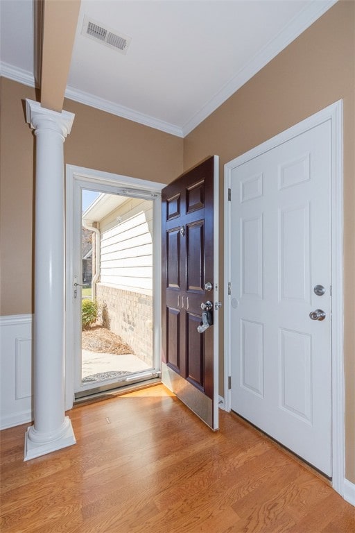 foyer featuring ornate columns, light hardwood / wood-style floors, and crown molding