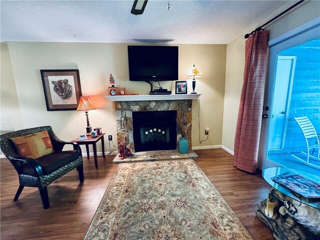 811 Northlake Dr, Anderson, SC 29625 - living room featuring wood finished floors, a textured ceiling, baseboards, and a stone fireplace