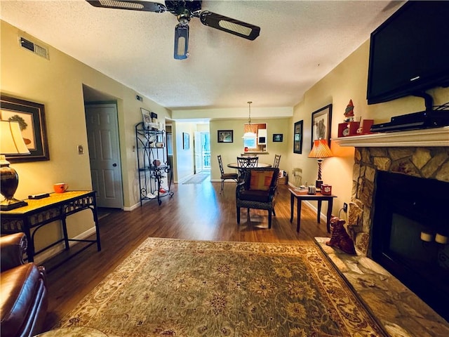 811 Northlake Dr, Anderson, SC 29625 - living room with dark wood-style floors, a textured ceiling, ceiling fan, a stone fireplace, and baseboards