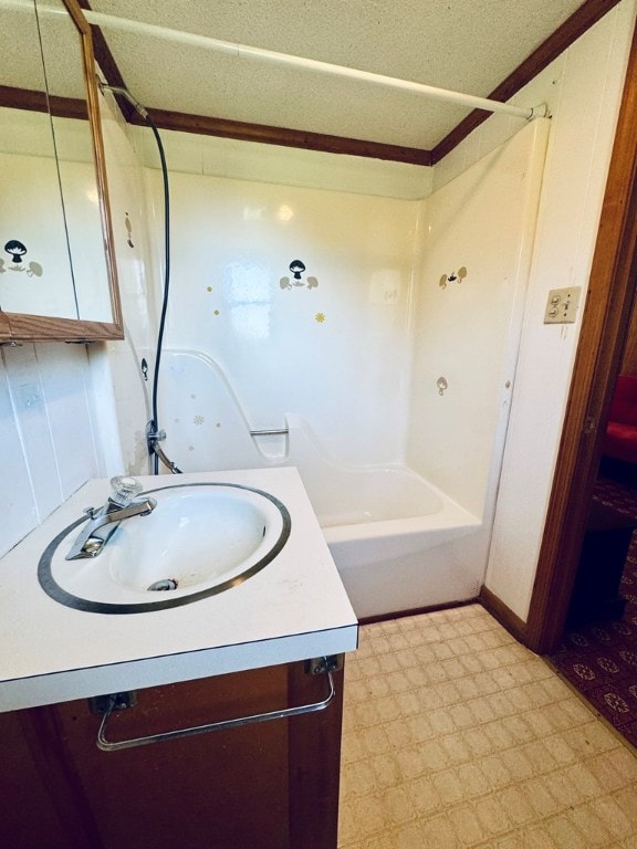 bathroom featuring vanity, shower / bathing tub combination, a textured ceiling, and ornamental molding