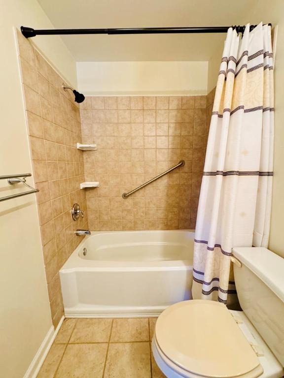 bathroom with tile patterned flooring, toilet, and shower / bathtub combination with curtain