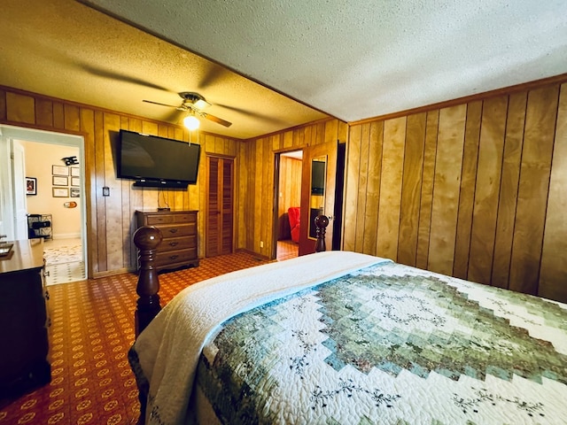 carpeted bedroom featuring ceiling fan, wood walls, and a textured ceiling