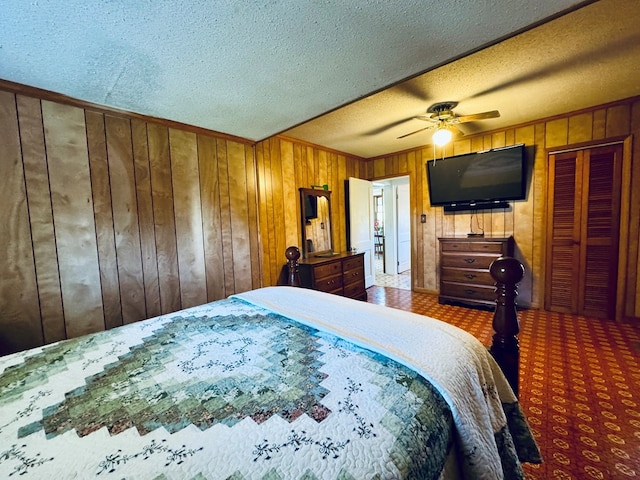 carpeted bedroom featuring ceiling fan, wood walls, and a textured ceiling