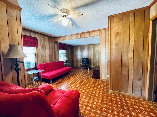 living room featuring ceiling fan, wood walls, and a textured ceiling