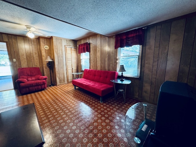 living room featuring a textured ceiling, wooden walls, and ceiling fan