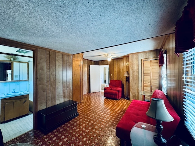 interior space featuring wooden walls, a textured ceiling, and ceiling fan