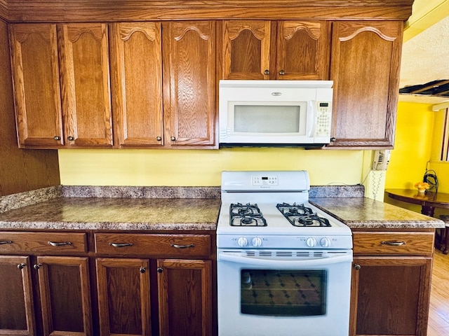 kitchen featuring white appliances and light hardwood / wood-style flooring