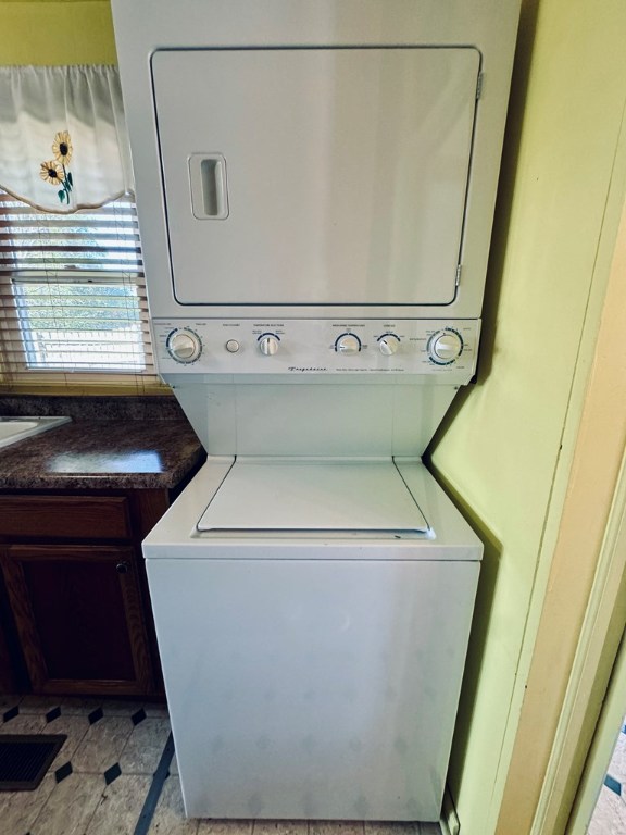 laundry room with stacked washing maching and dryer and cabinets