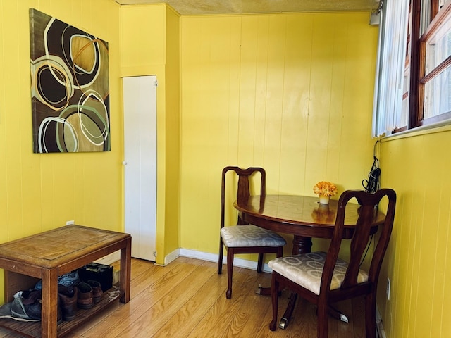 sitting room with wooden walls, light hardwood / wood-style flooring, and a textured ceiling