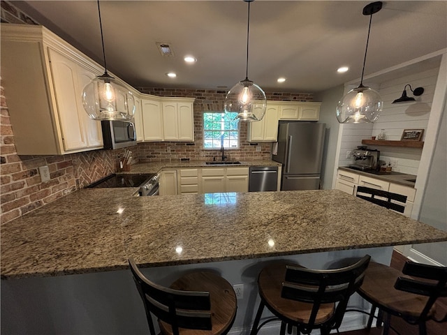 kitchen featuring backsplash, appliances with stainless steel finishes, pendant lighting, and a kitchen bar