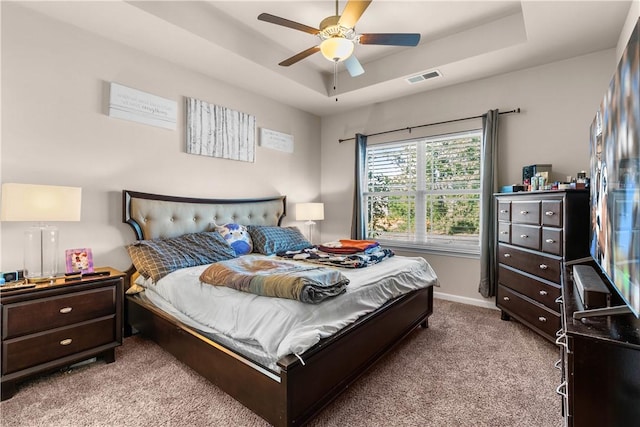 carpeted bedroom featuring a raised ceiling and ceiling fan