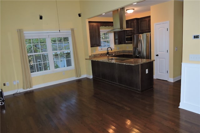 kitchen with kitchen peninsula, stainless steel appliances, stone countertops, and dark hardwood / wood-style flooring